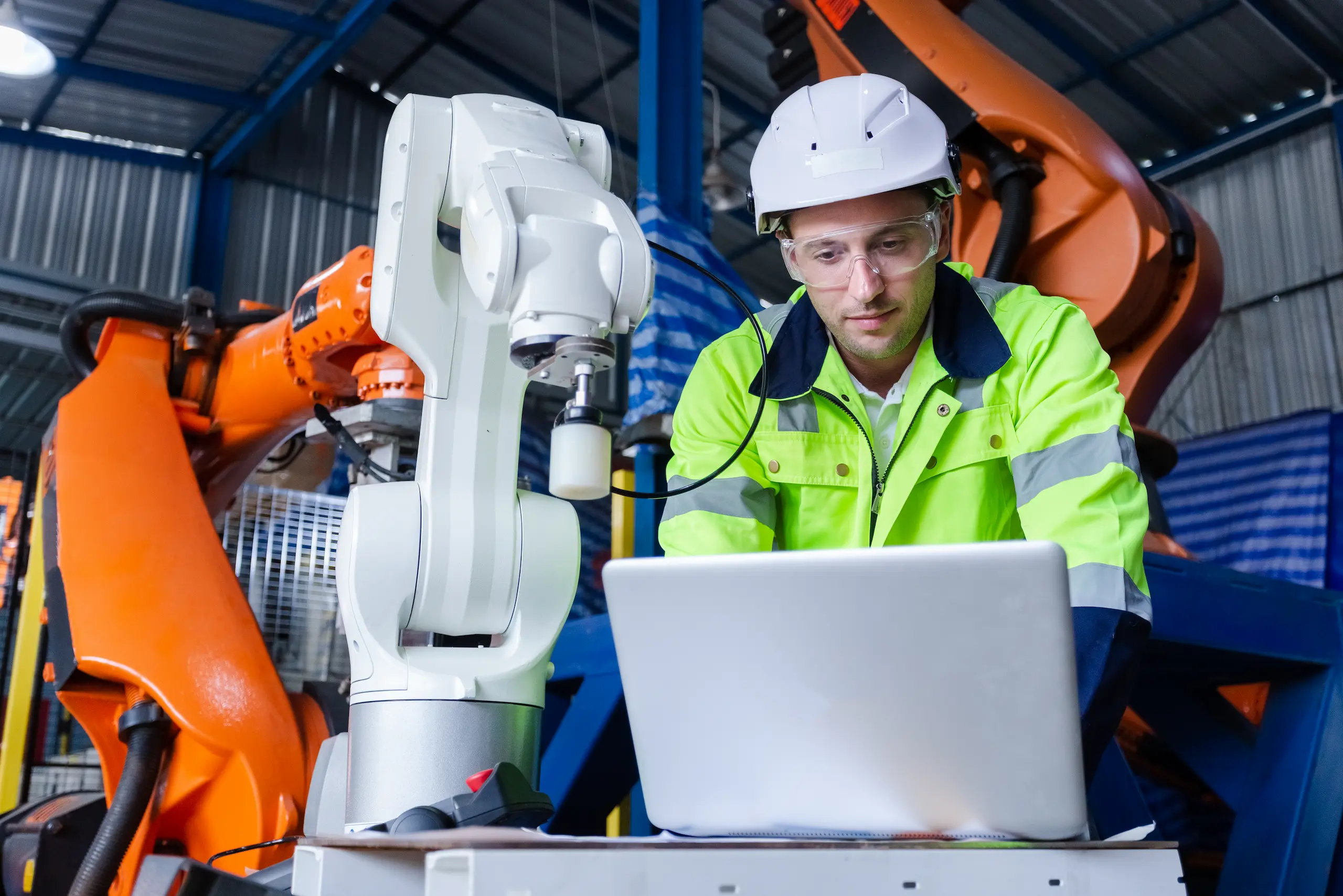 protectores-contra-sobretensiones-equipos-industriales-sensibles Operarios felices de trabajar de manera segura con protectores contra sobretensiones en ambientes industriales. Brazo robótico de control portátil automatizado. Automatización robótica